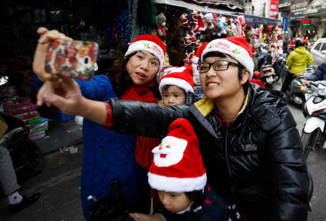 Chu Bich Thuy (left) and her children are pictured wearing Santa Claus hats and taking a selfie on Hang Ma Street in Hanoi.