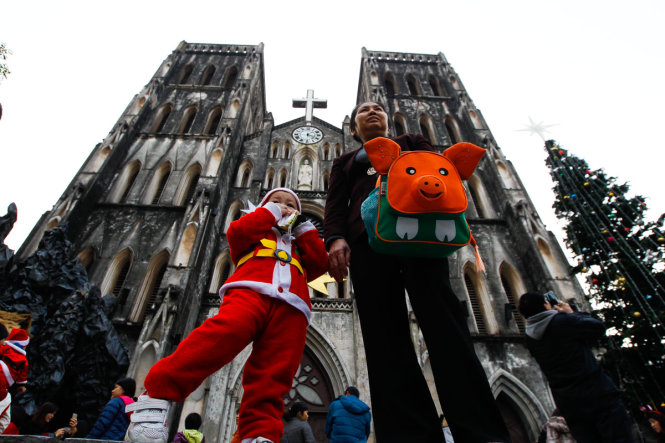 A boy wearing Santa Claus clothes is seen going to the church in Hanoi with his family member.