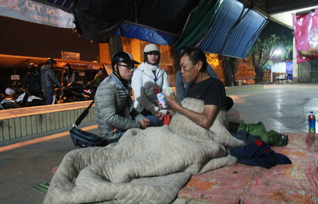 Two members of the Trai Tim Viet (Vietnamese Hearts) Club in northern Vietnam's Hai Phong City are pictured gifting milk and warm clothing to a homeless man on New Year's Eve.