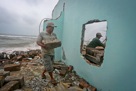 A local is seen gathering leftover stone slabs after his family’s home was torn apart by massive waves in late December 2014.
