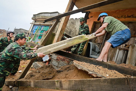 Tuy Hoa City’s border guards are pictured helping a local household fix their home, which was partly damaged by the waves.