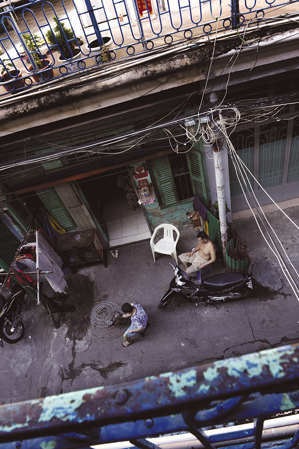 Each alley is a public space of residents living in the area. A boy is seen feeding a chicken in this photo.