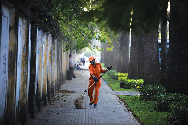 A sanitation worker does his job on Nguyen Binh Khiem Street, District 1, where century-old trees seem to be greener in the cold weather. 