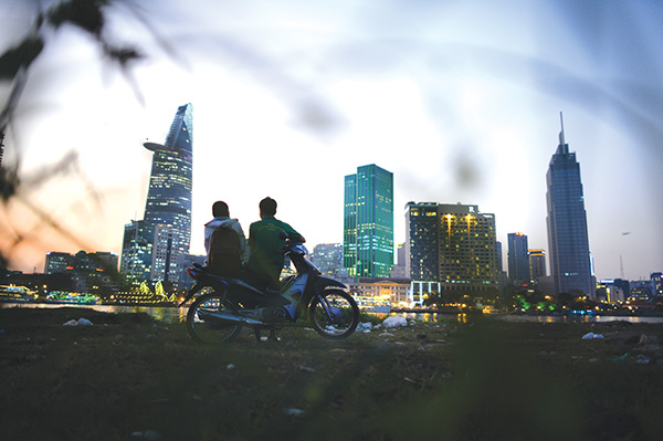 This picture captures a couple enjoying the cold breeze by the Saigon riverside against the skyline of Ho Chi Minh City. 