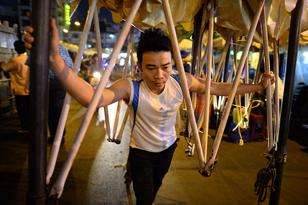 A man is pictured pushing his tent system, with wheels and light bulbs attached, to Ben Thanh night market.