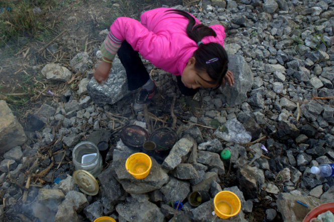 A young girl is seen trying to build a fire.