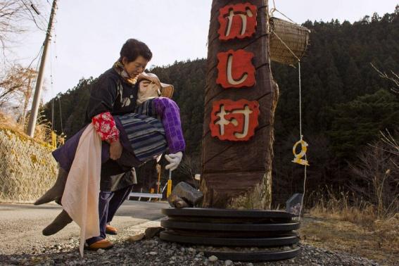 Tsukimi Ayano carries a scarecrow to place it on the road leading into the mountain village of Nagoro on Shikoku Island in southern Japan February 24, 2015.