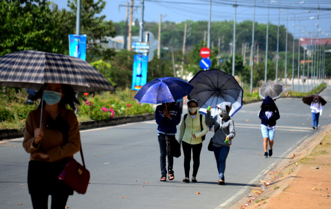 Some students of the Vietnam National University-Ho Chi Minh City carry umbrellas to shield themselves from the scorching sun.