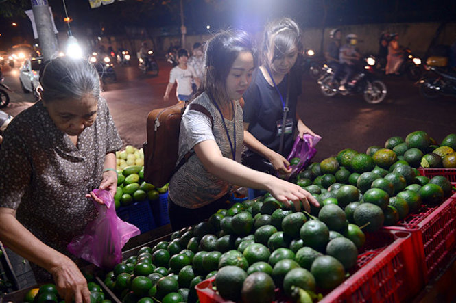 An elderly woman and two girls are seen buying oranges to make juice and relieve themselves of thirst and irritability during the hot days.