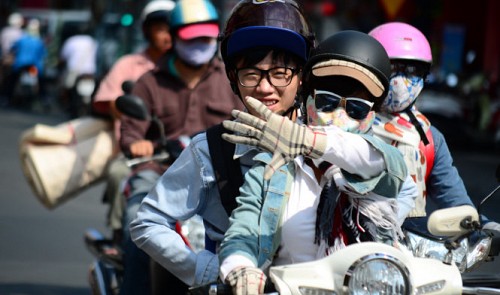 A woman is armed with sunglasses, a mask, hat, scarf and gloves while driving in the blazing heat.