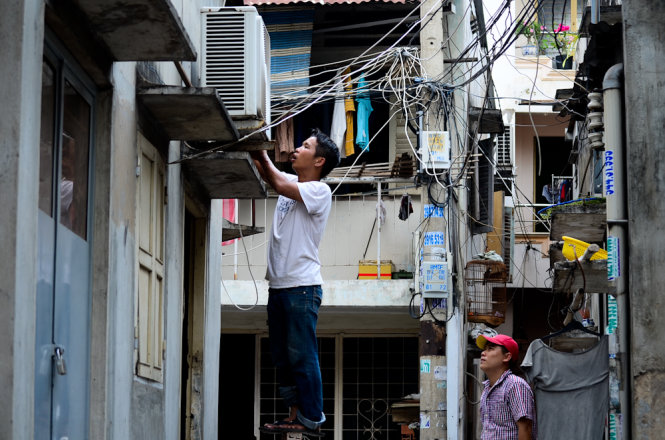 A man in Binh Thanh District has his air conditioner fixed after it has been overworked during the past few weeks