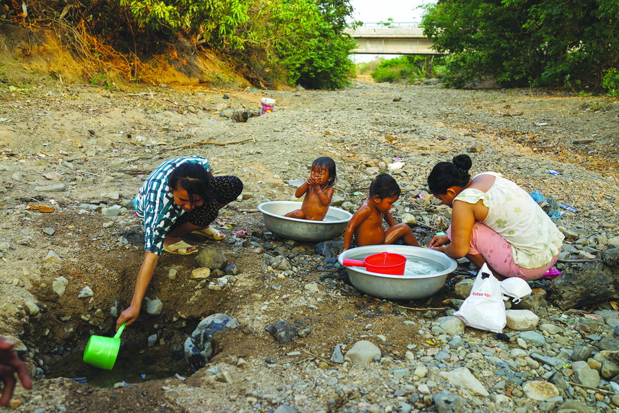 Women and children from Ra Giua Hamlet take a bath and wash clothes at an underground water pit in the middle of a spring’s dried-up bed. The hamlet is far away from the government’s reverse cistern so people there depend on natural underground water.