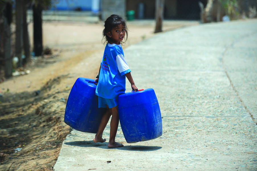 A kid helps her family to bring water home when tankers carrying water from other locations arrive.