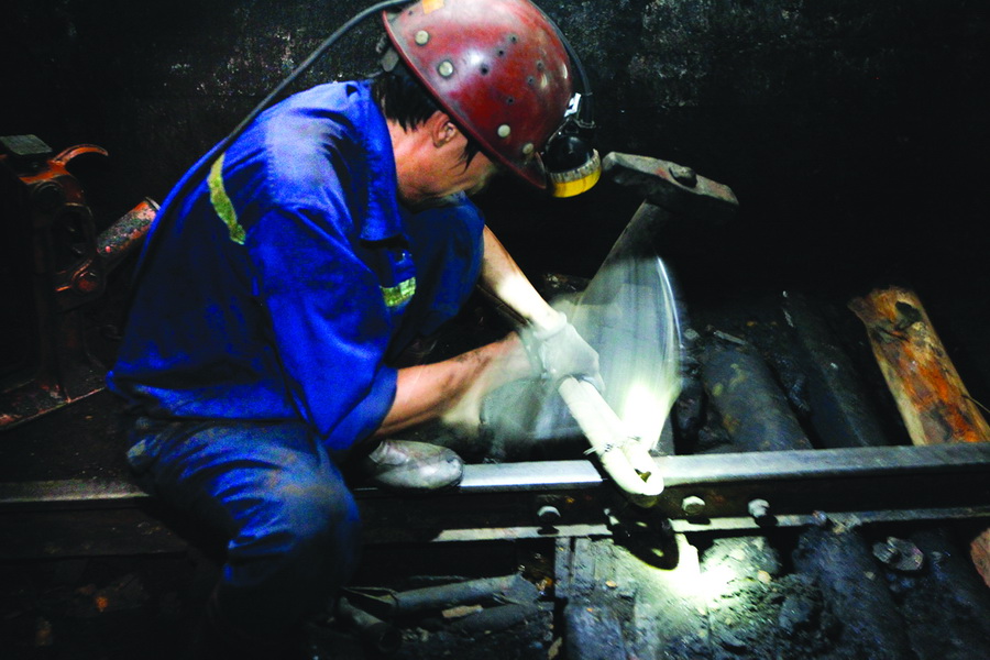 A worker repairs a track in the mine. Transferring coal from the exploration area out of the mine is an important part of their job.