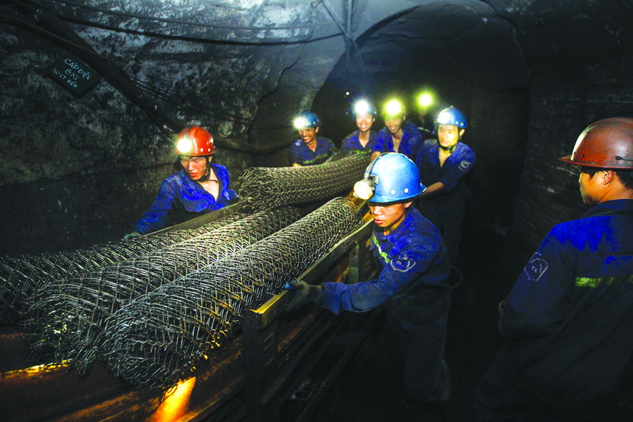 A group of workers carry steel nets into the mine
