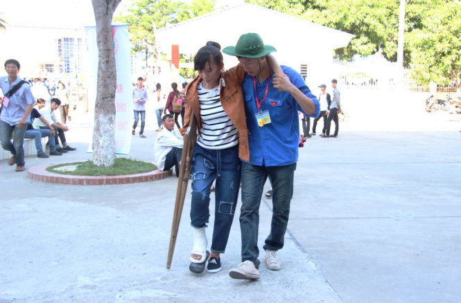 A volunteer helps Phan Thi Tam, a student from Mai Thuc Loan High School in the northern province of Ha Tinh’s Loc Ha District, walks with a crutch to her exam venue for registration in Vinh City in Nghe An Province on June 30, 2015. Tam said she broke her right leg in a road accident a month ago. She added that she was about to give up because she thought she could not come to the exam venue, but thanks to the support from family and friends, she is determined to pass this important exam.