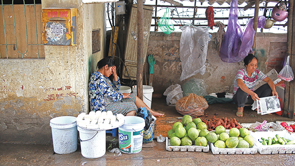 A woman who sells tofu is pictured sleeping next to her stall, with her hand against her forehead.