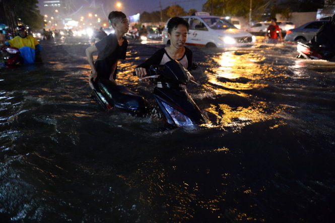 Two young people are seen trying to push their motorbike through a seriously submerged section of Nguyen Huu Canh Street in Binh Thanh District, Ho Chi Minh City on the evening of September 15, 2015. Photo