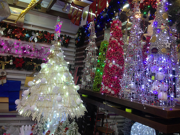 Christmas trees are decorated with LED chain lights for sale at a store in District 1.