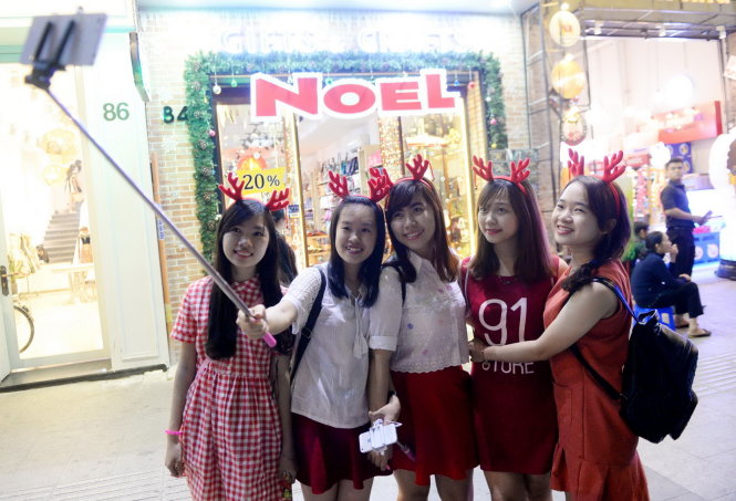 A group of young girls wearing red deer horns take a wefie on the street.