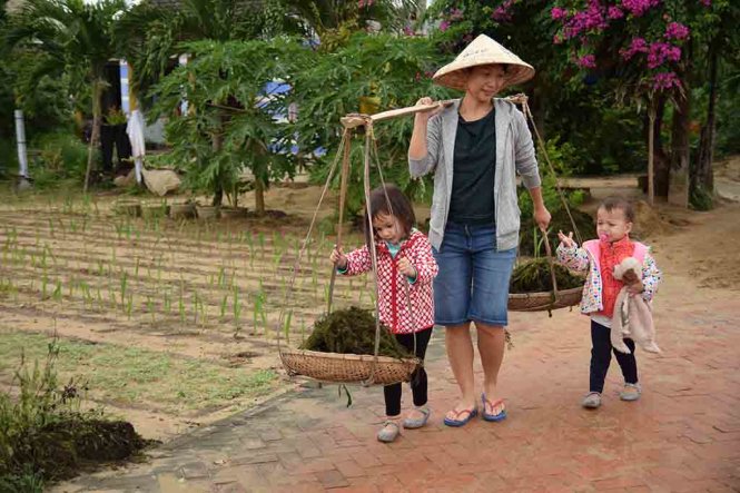 Stirling’s mother carries the ganh, bamboo yokes hung with baskets at each end used to carry vegetables around, while Stirling and her younger brother walk alongside.