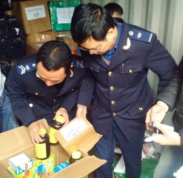 Vietnam customs officers hold container of alcohol, used electronic products shipped from US