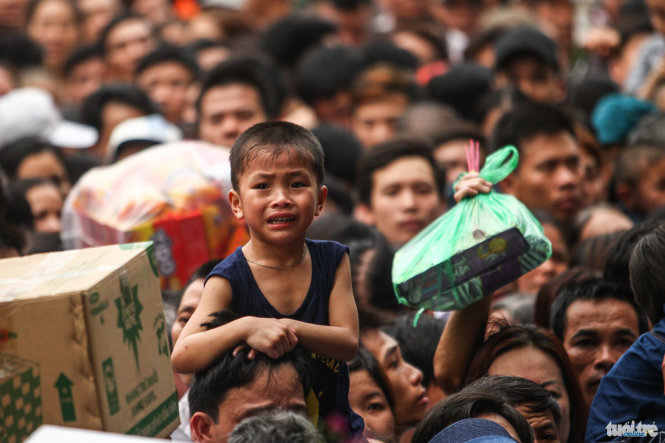 A boy cries as he and his father are stuck in the overwhelming sea of people attending the Hung Kings festival at the Hung Temples Relic Site in Phu Tho Province, April 16, 2016