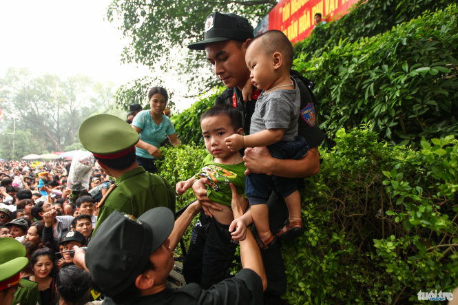 Two boys are taken by police officers to a separate place for safety reasons during the Hung Kings festival at the Hung Temples Relic Site in Phu Tho Province, April 16, 2016.