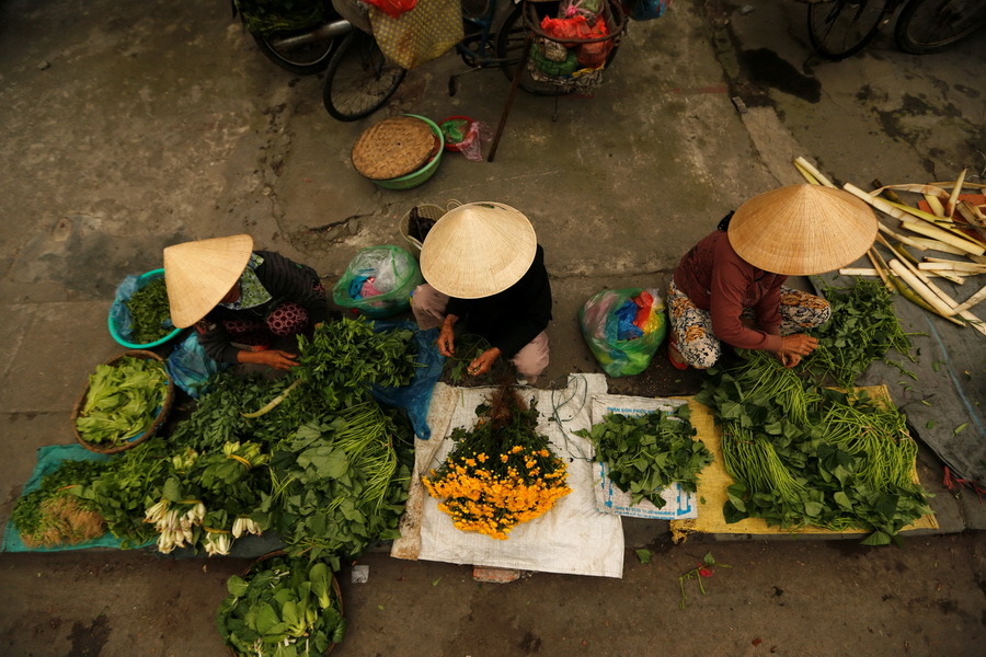Women wearing traditional hats, known as a non la, sit in a market in Hoi An, Vietnam April 5, 2016.