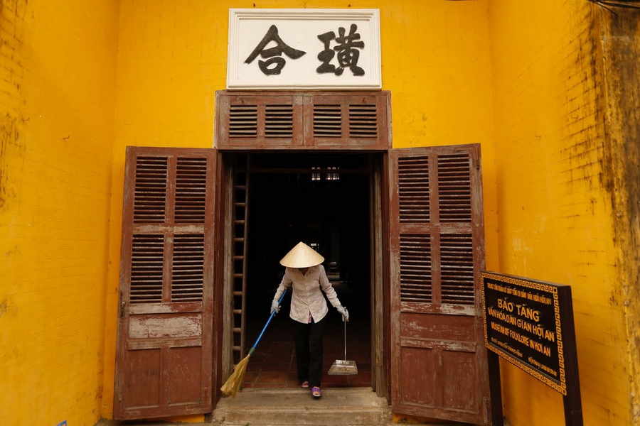 A woman wear a non la while cleaning the Museum of Folklore in Hoi An.