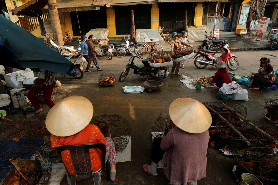 Women wearing traditional hats, known as a non la, sit in a market in Hoi An, Vietnam April 7, 2016.