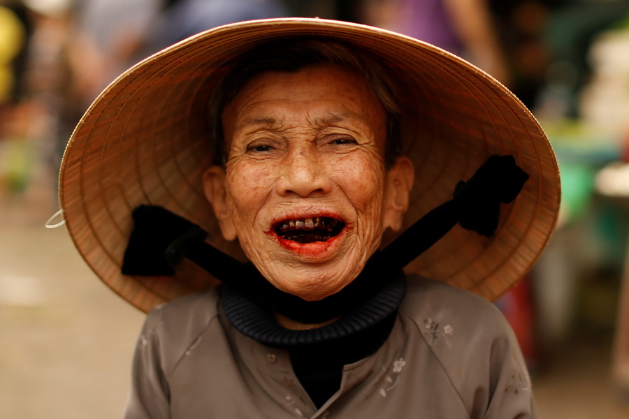 A woman wearing a traditional hat, known as a non la, poses for a portrait at a market in Hoi An, Vietnam April 5, 2016.