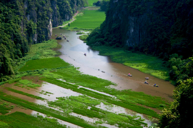 The Ngo Dong River with small boats curves through the limestone mountains.