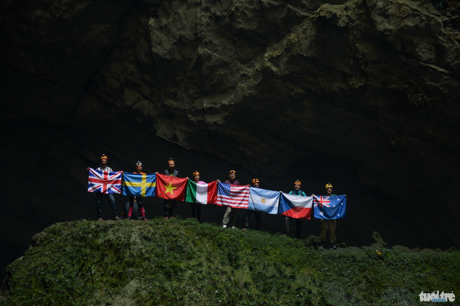 The diplomats pose with their national flags at the first sinkhole.