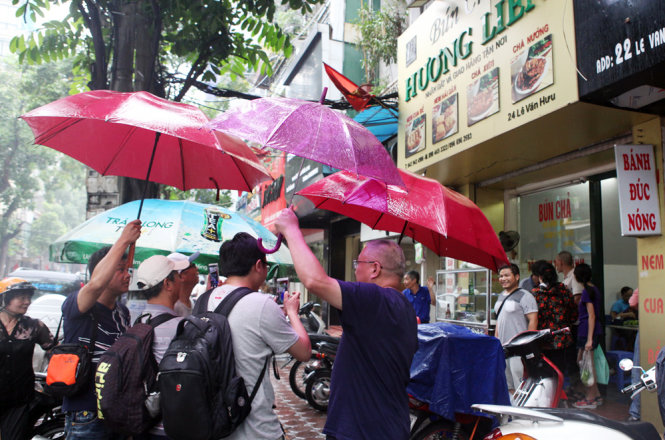 A number of dinners walk to Huong Lien Outlet with umbrellas due to the rain