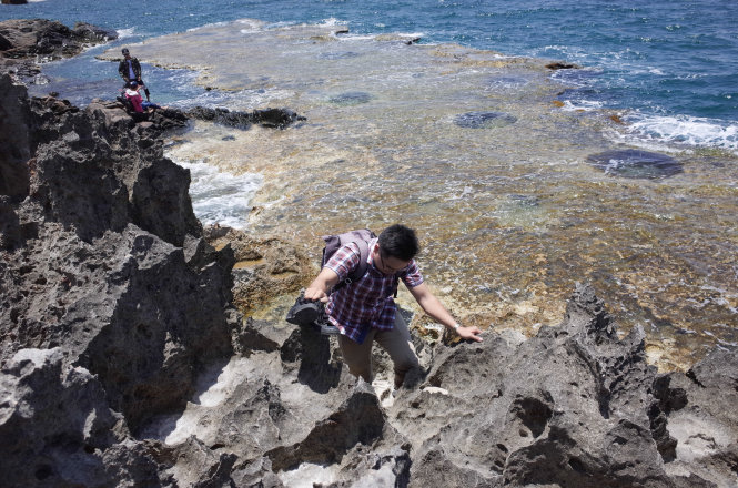 Tourists climb over sharp stones. 