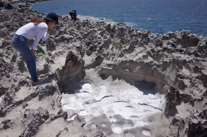 A tourist watches salt crystallized in a rut