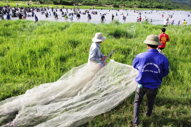 Three people are seen carrying their fishing nets to the swamp.