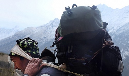 A porter carries a large load of luggage on the Himalayas.
