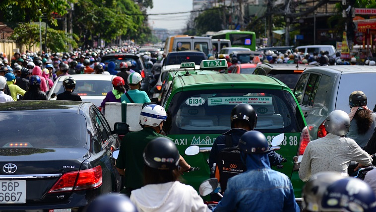 Motorbikes zigzag between cars and taxis.