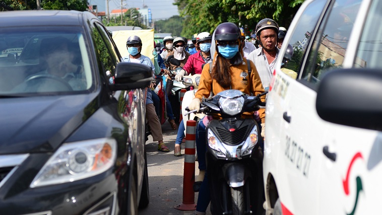 Motorbikes zigzag between cars and taxis.