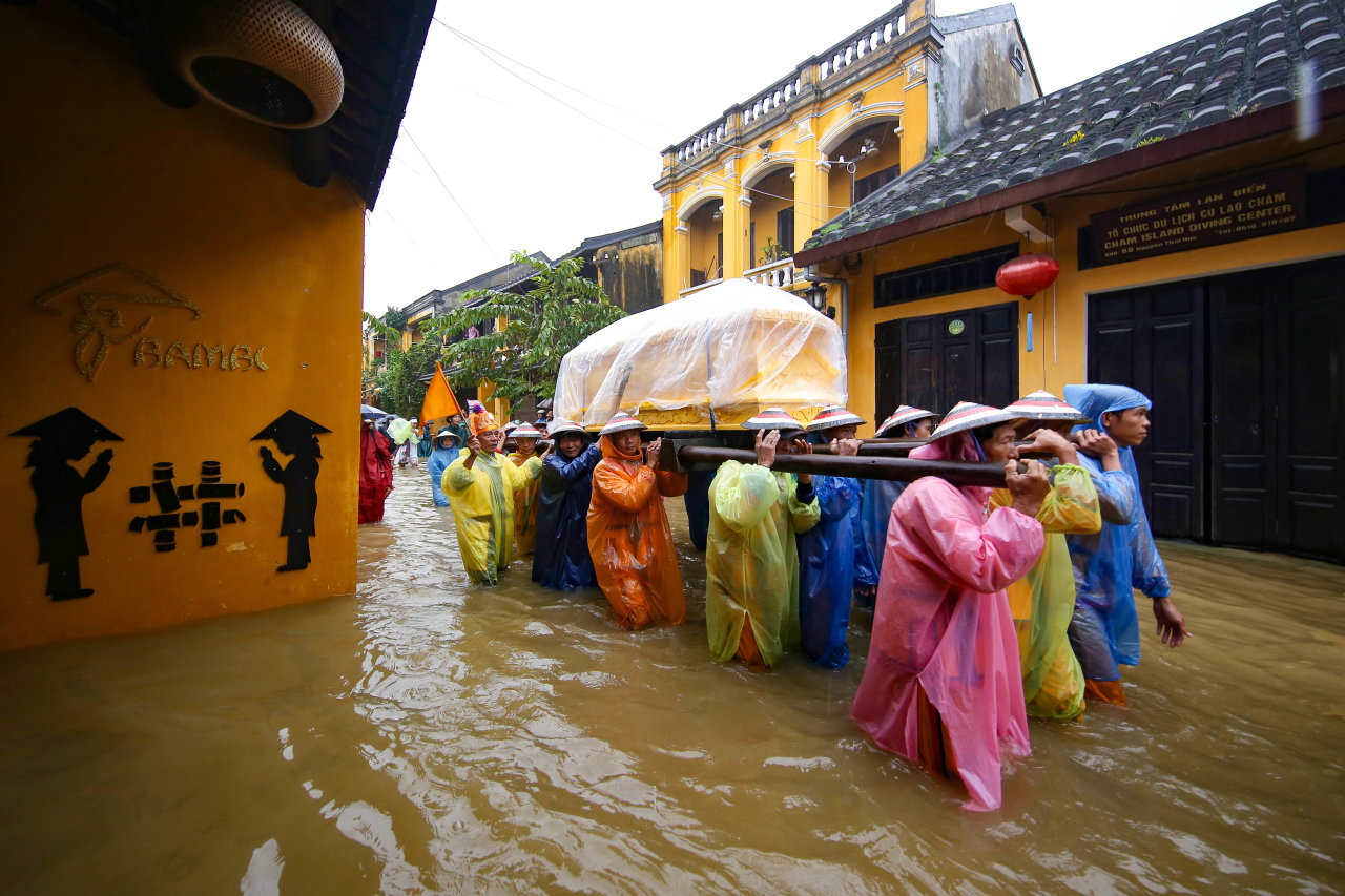 Mourners struggle to carry coffin in flooded Hoi An