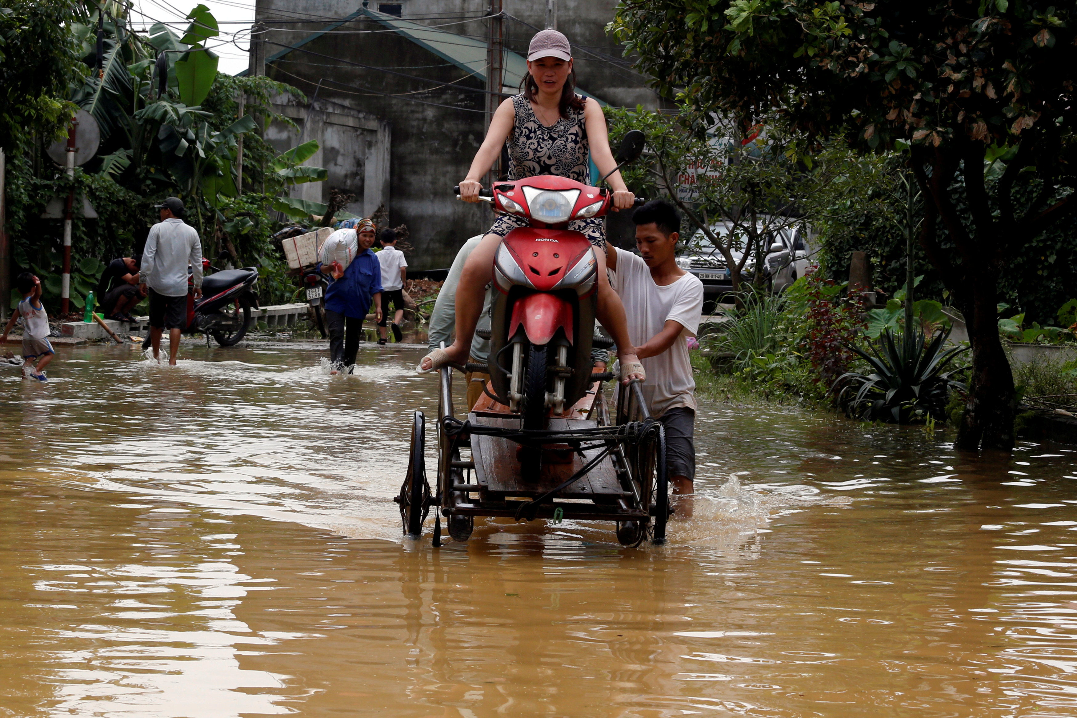 Men evacuate a woman through a flooded road after a tropical depression in Hanoi, Vietnam October 13, 2017. Photo: Reuters