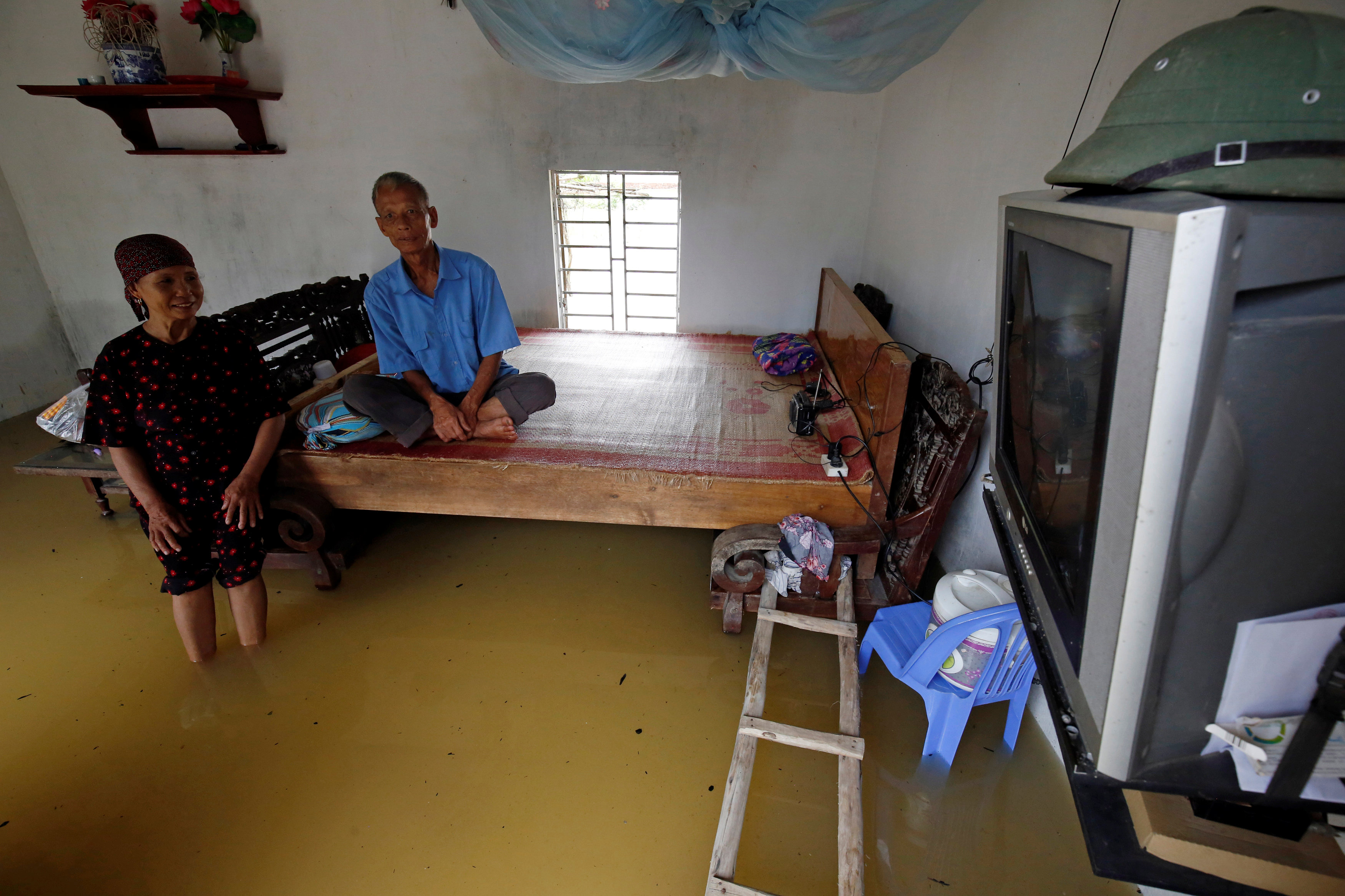A couple watches TV in their flooded house after a tropical depression in Hanoi, Vietnam October 13, 2017. Photo: Reuters