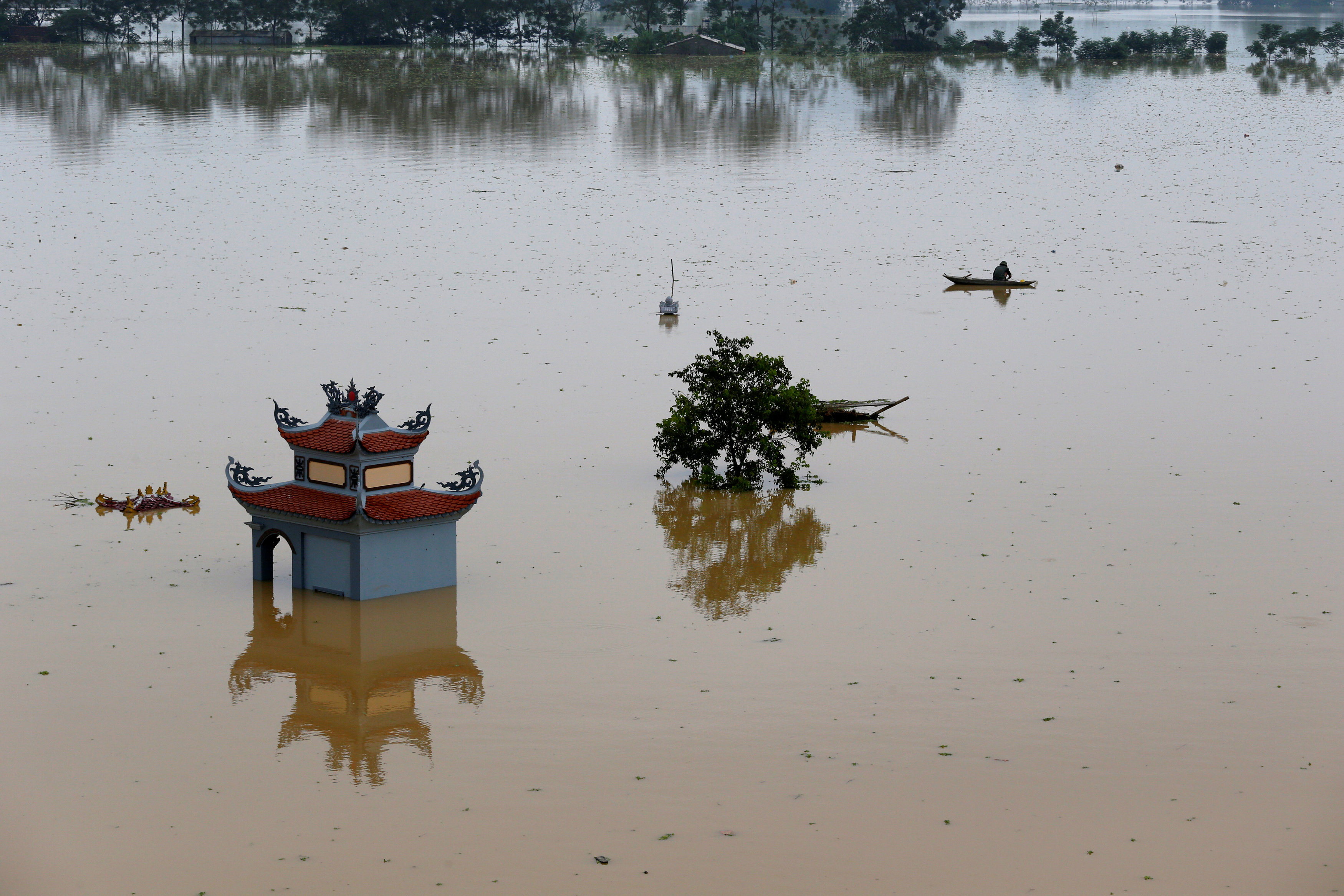 A farmer catches fish in a flooded village after a tropical depression in Hanoi, Vietnam October 13, 2017. Photo: Reuters
