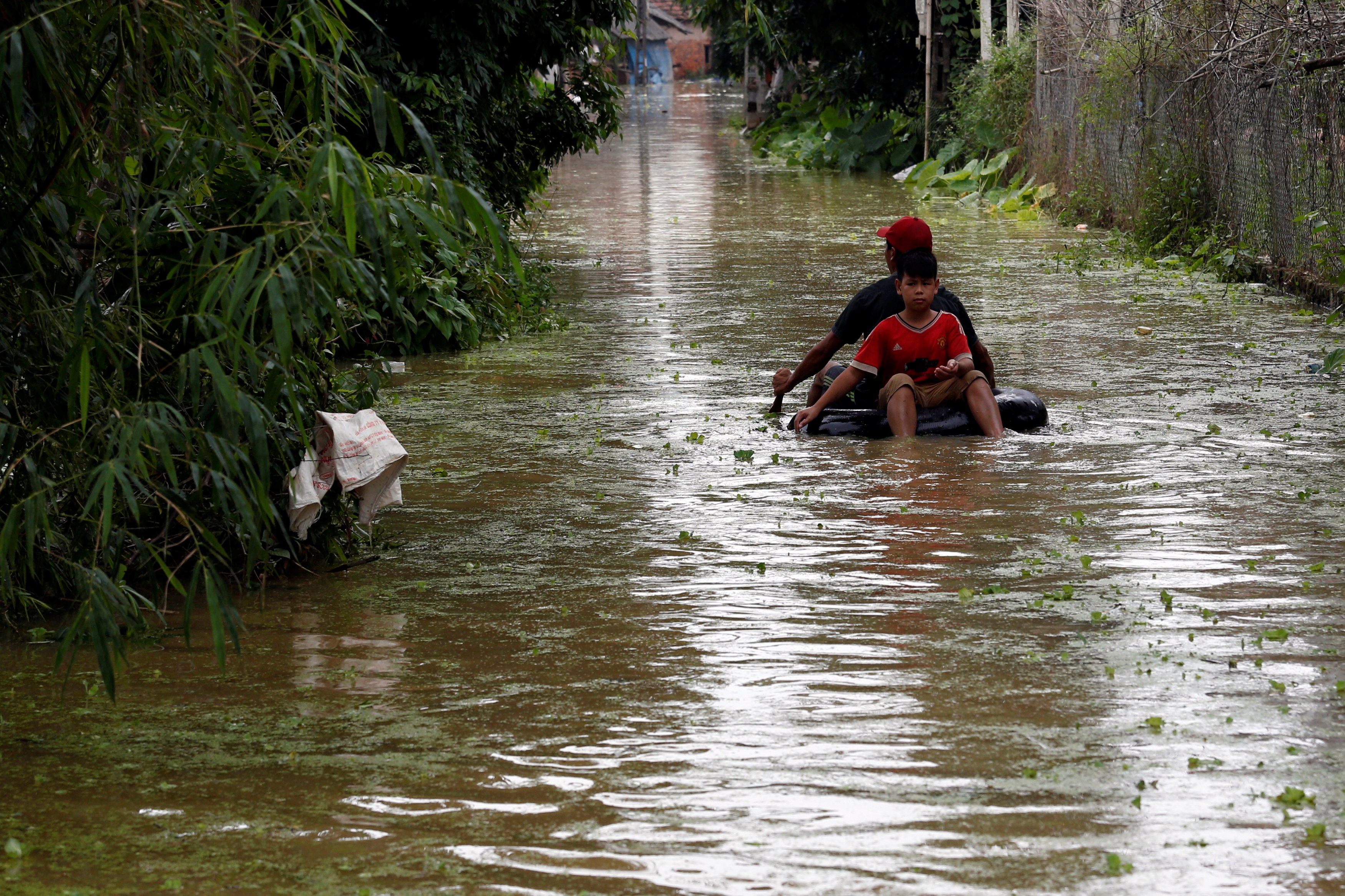 Boys paddle an improvised boat in a flooded village after a tropical depression in Hanoi, Vietnam October 13, 2017. Photo: Reuters