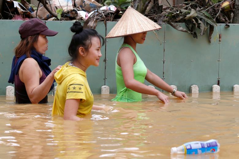 Women wade along submerged by Typhoon Damrey houses in the UNESCO heritage ancient town of Hoi An, Vietnam. Photo: Reuters