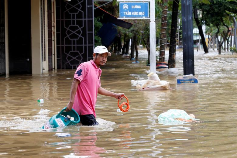A man wades with a gas tank along submerged by Typhoon Damrey houses in the UNESCO heritage ancient town of Hoi An, Vietnam. Photo: Reuters