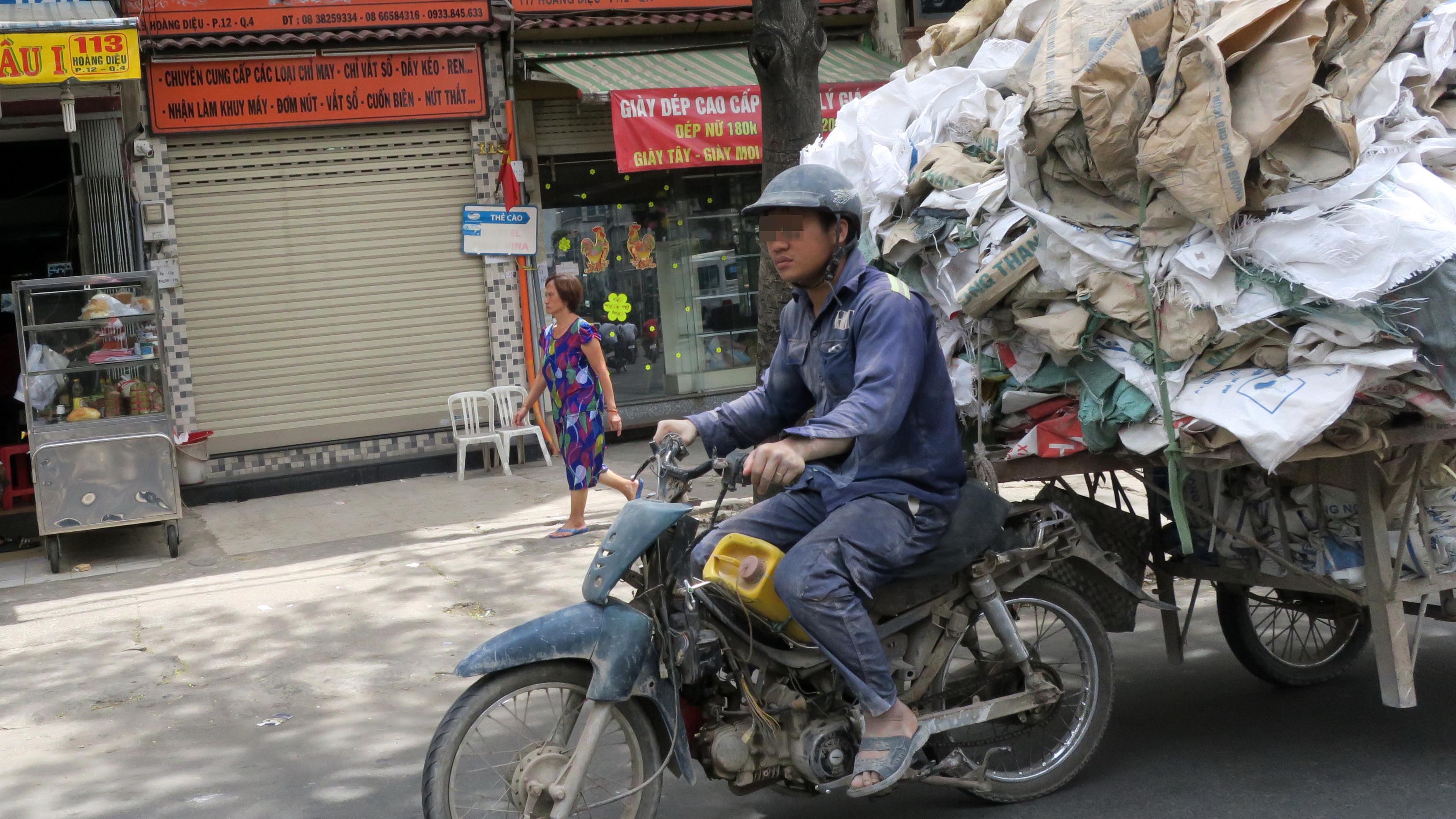 A man rides a ramshackle motorbike pulling bags on a cart as part of his daily job. Photo: Tuoi Tre