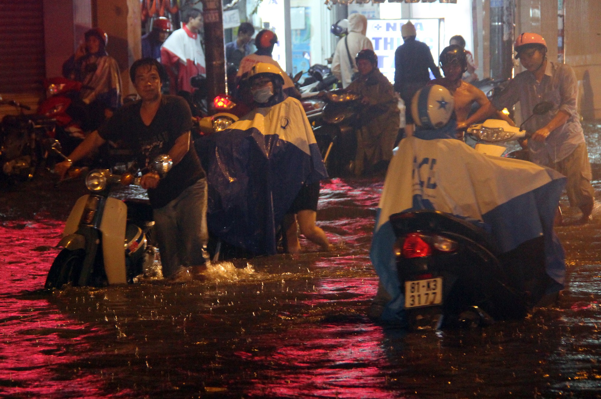 Riders have to walk their bikes through knee-deep water in Ho Chi Minh City. Photo: Tuoi Tre